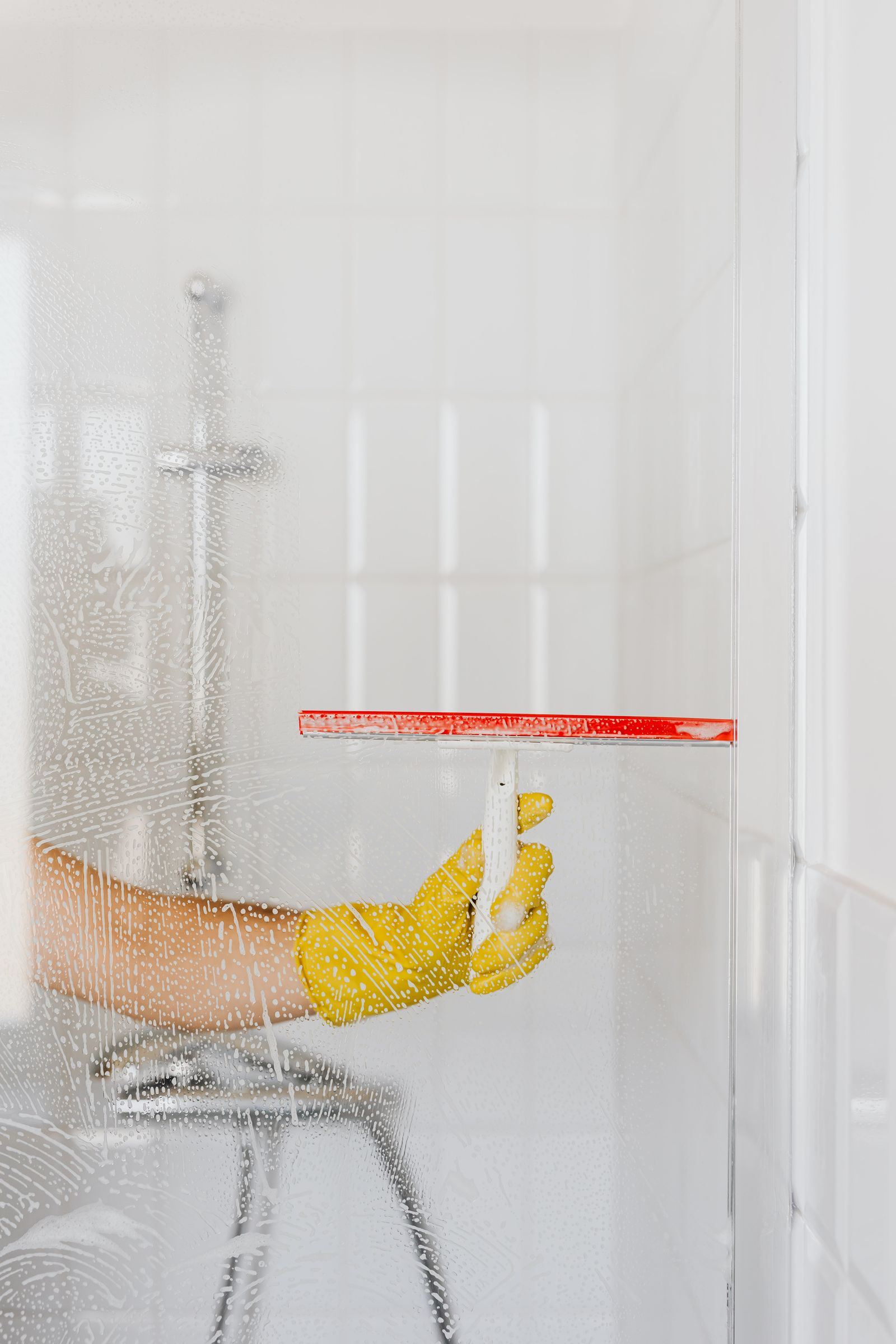 Yellow cleaning glove and squeegee used on a glass surface