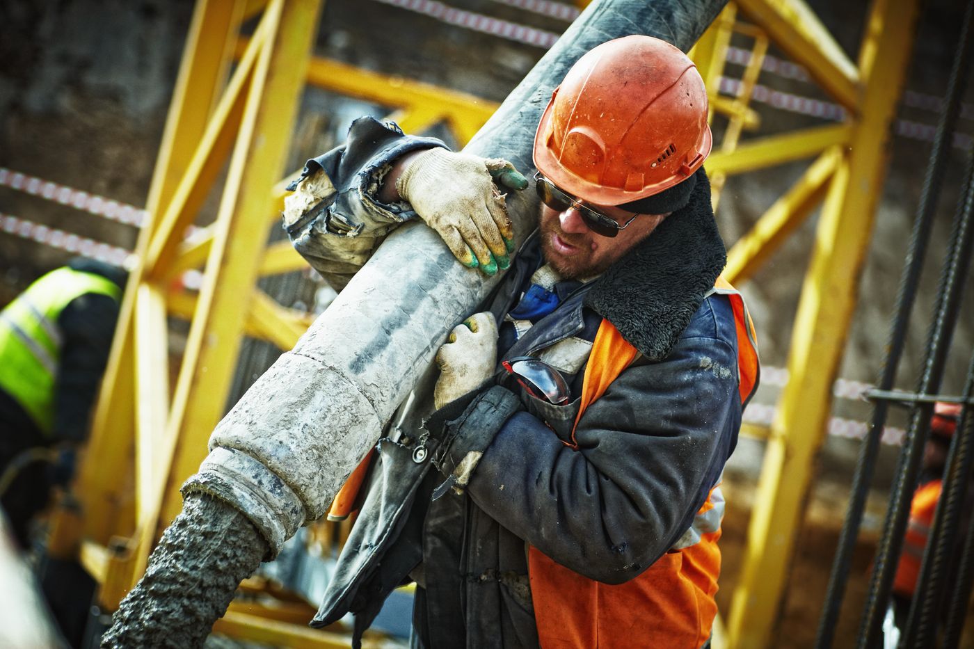 Worker on a jobsite wearing a hard hat, high-visibility vest, and gloves